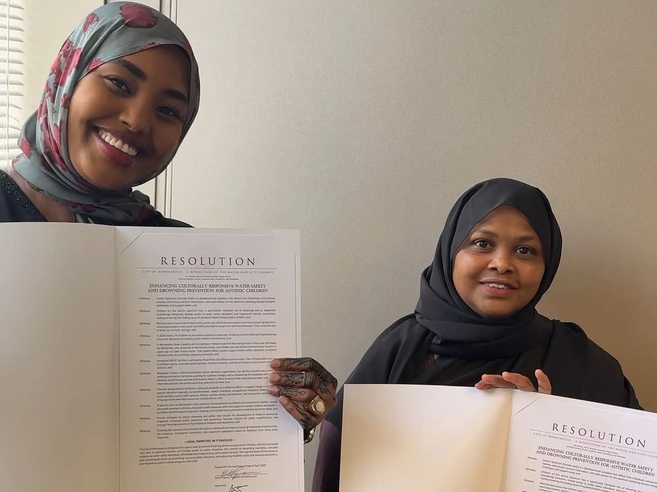 Two women from the Maangaar Voices community smile as they hold up proclamations.