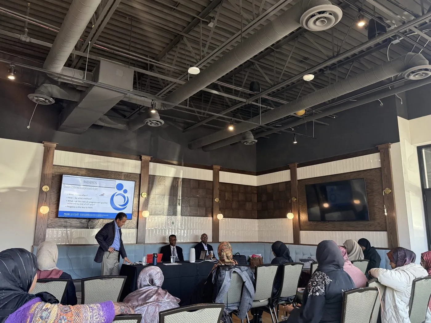 A room set up for a community event, with a presentation on screen.