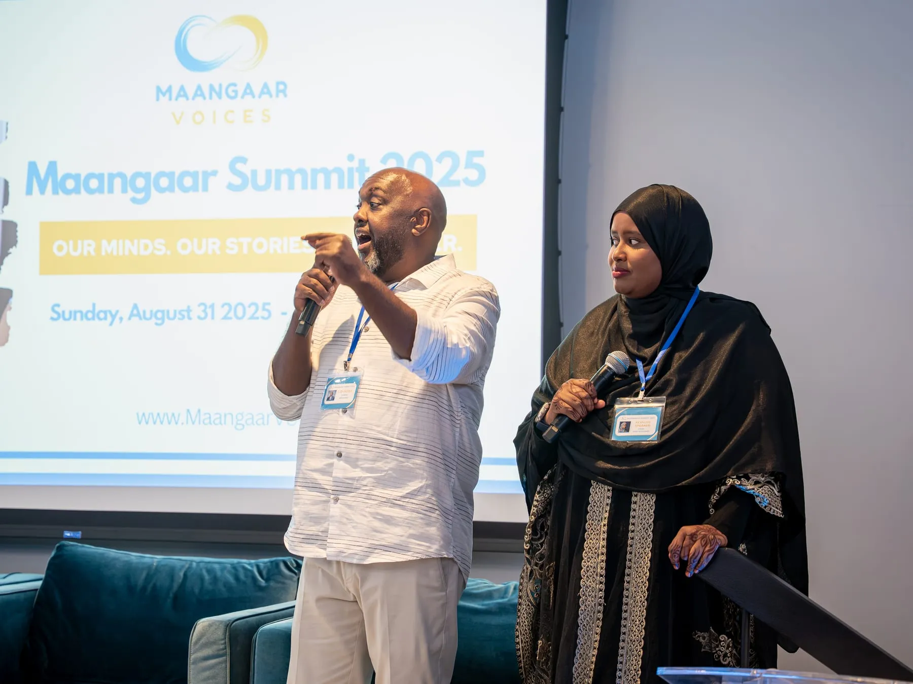 Two speakers with microphones address the room in front of the welcome slide: Maangaar Summit 2025, Our Minds. Our Stories. Our Power., Sunday, August 31, 2025.