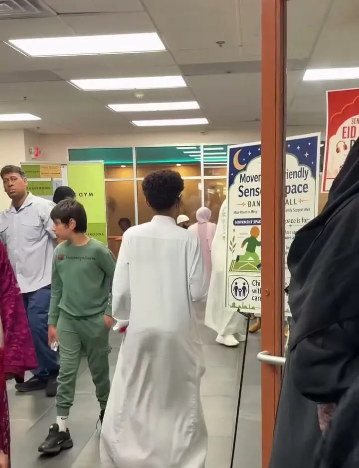 Families arrive in the hall beside the Movement-Friendly Sensory Space sign.